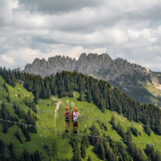 deux adultes traversent la passerelle de la via ferrata de Charmey avec la vue sur les Gastlosen