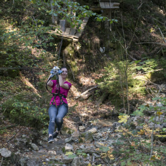 Une adulte se laisse glisser sur la tyrolienne de Charmey