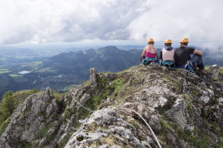 Des adultes sont assis au sol au sommet de la via ferrata avec leur matériel