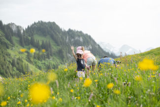 Une famille joue dans les prés avec une vue sur les montagnes de Charmey