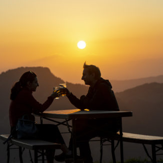 Un couple trinquant sur la terrasse du sommet de Charmey au coucher de soleil