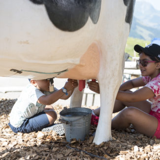 deux enfants qui traient une fausse vache au sommet des remontées mécaniques de Charmey