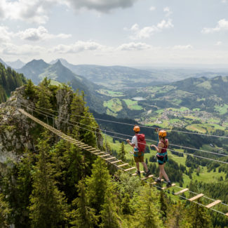 Deux personnes sur une passerelle suspendue faisant partie de la via ferrata de Charmey