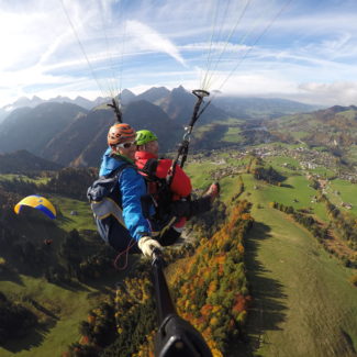 Un parapente biplace survolant la vallée de Charmey