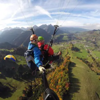 Un parapente biplace survolant la vallée de Charmey