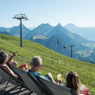 Des amis prennent l'apéro au sommet des remontées mécaniques avec la vue sur les télécabines et la vallée